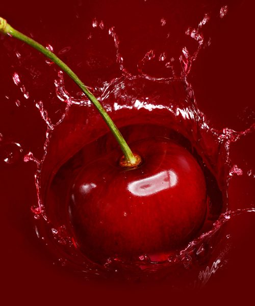 Cherry falling into the juice with huge splashes